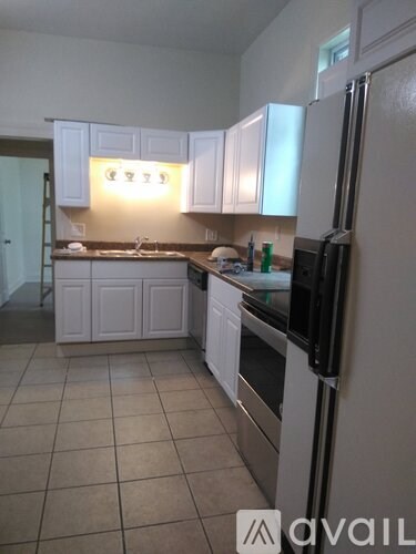 A kitchen with white cabinets and a black fridge.