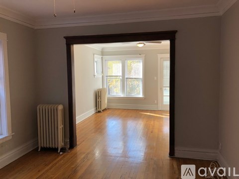 A room with a wooden floor and a window with a view of trees outside.