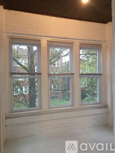 A room with a white brick wall and two windows.