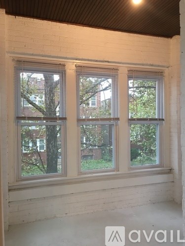 A room with a white brick wall and two windows.
