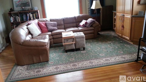 A living room with a brown leather couch and a rug.