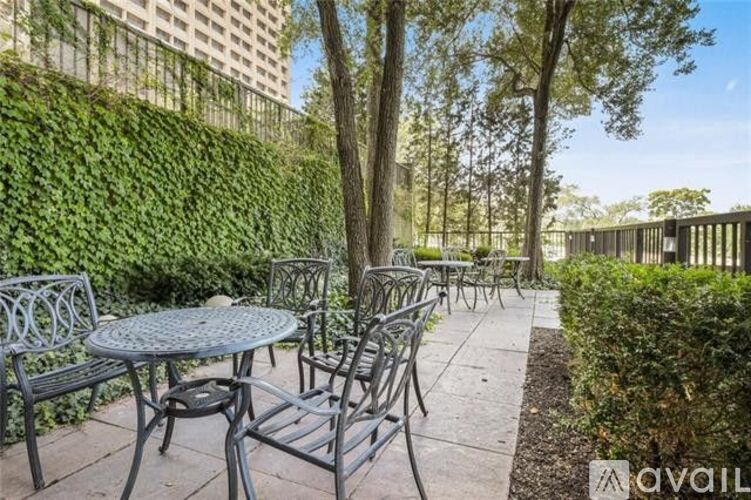 A patio with a table and chairs surrounded by greenery.