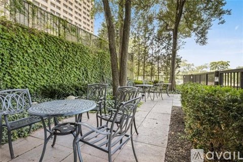 A patio with a table and chairs surrounded by greenery.