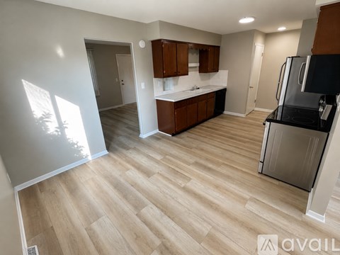 A kitchen with wooden cabinets and a black fridge is available for rent.