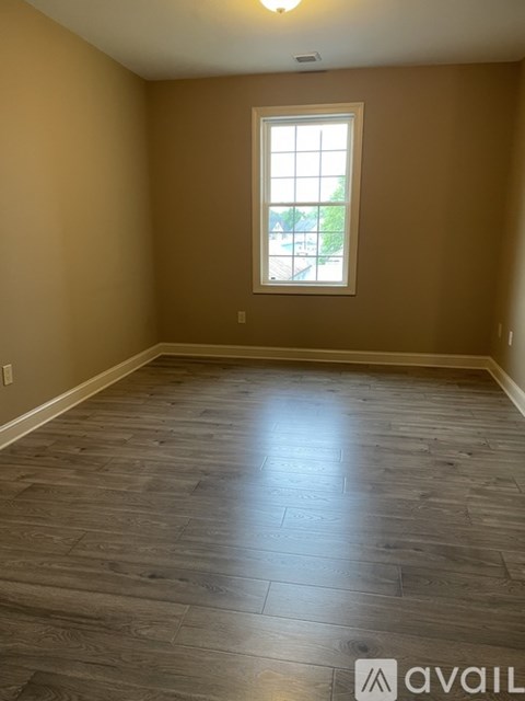 A room with a window and wooden flooring.
