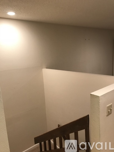 A white wall with a light switch and a wooden staircase.