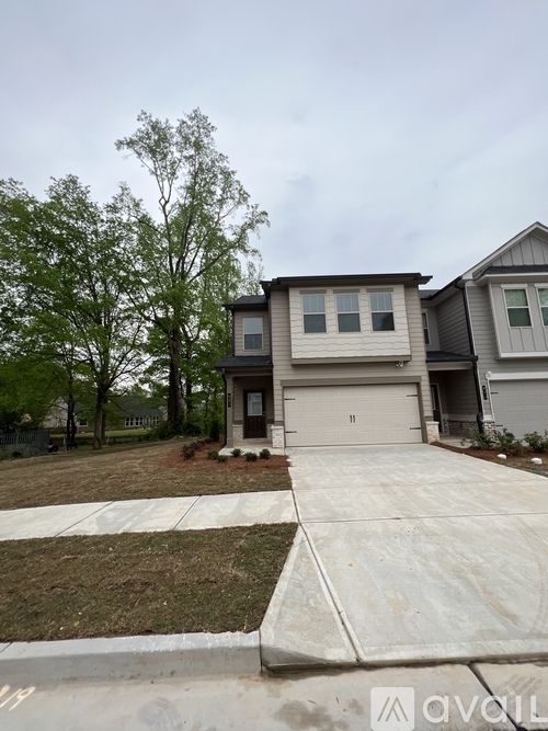 A house with a grey garage door is in front of a tree.
