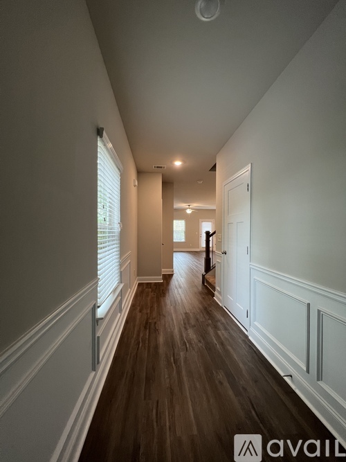 A long hallway with wood floors and white walls.