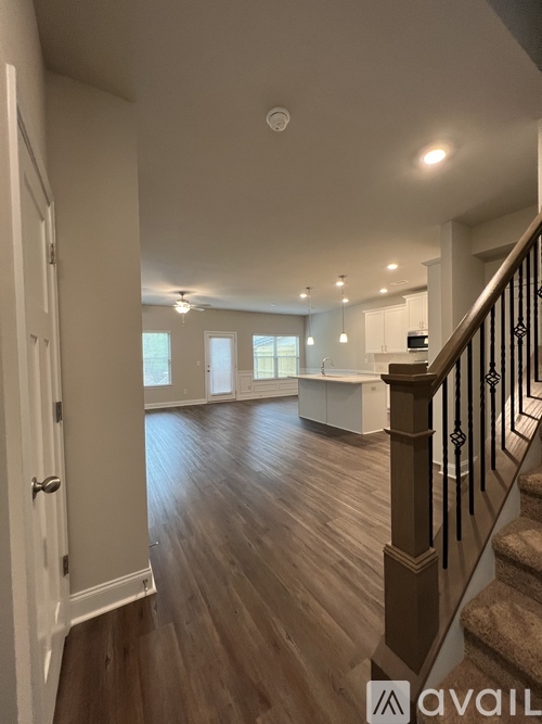 A spacious room with wooden floors and a staircase with a railing.
