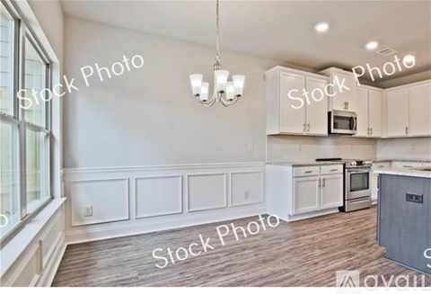 A kitchen with white cabinets and a wooden floor.
