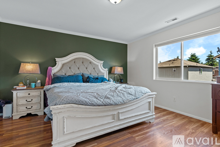 A bedroom with a large bed and a window overlooking a house.