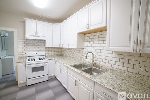 A kitchen with white cabinets and a white stove top oven.