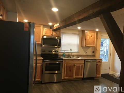 A kitchen with a black refrigerator and stainless steel appliances.