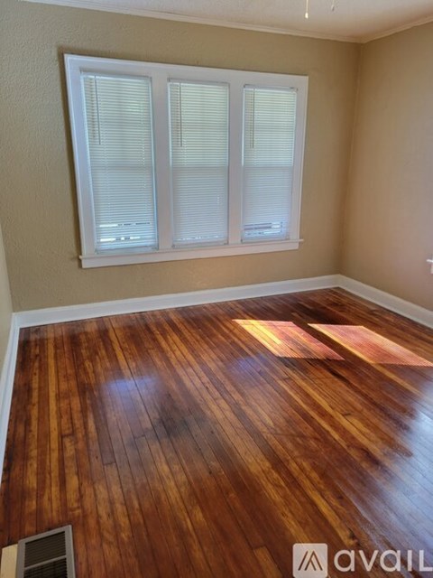 A room with wooden flooring and a window with blinds.