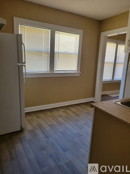 A kitchen with a white refrigerator and wooden floors.