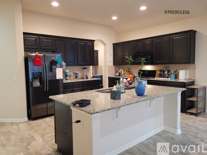 A kitchen with black cabinets and a granite countertop.