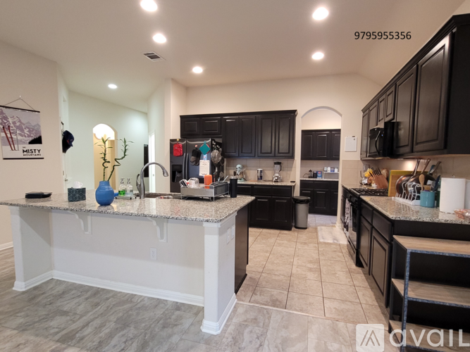 A kitchen with a white island in the middle and black cabinets.