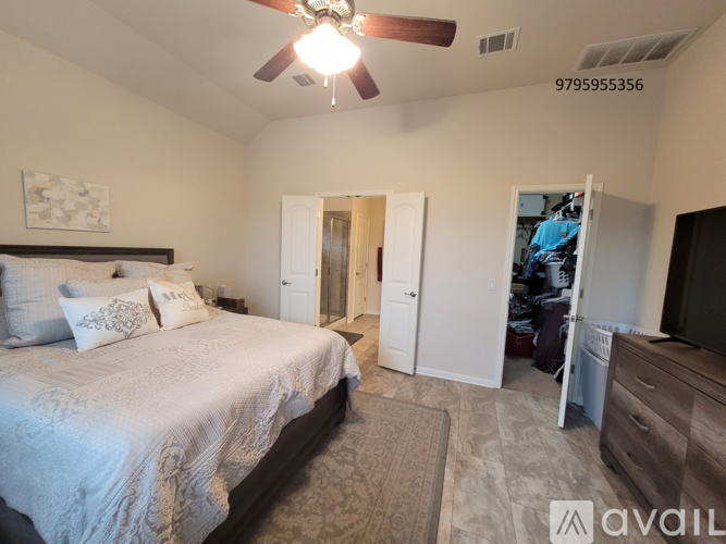 A bedroom with a large bed and a ceiling fan.