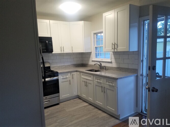 A kitchen with white cabinets and a black microwave.