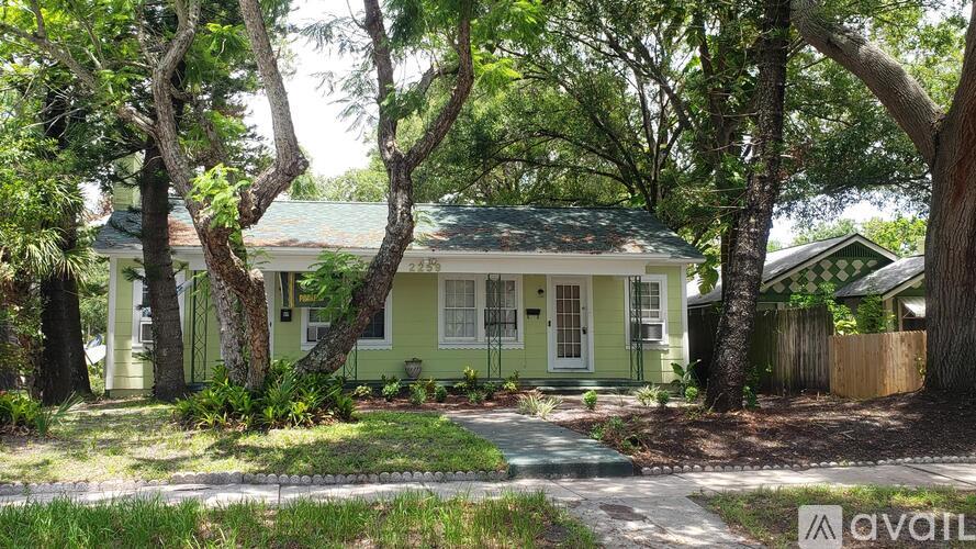 A house with a green front yard and trees surrounding it.