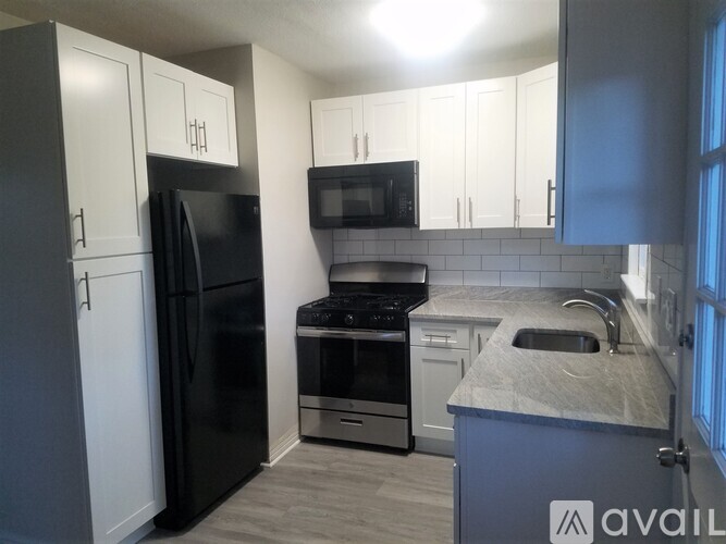 A kitchen with a black refrigerator, stove, and microwave.