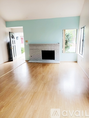 A living room with a fireplace and wooden floors.