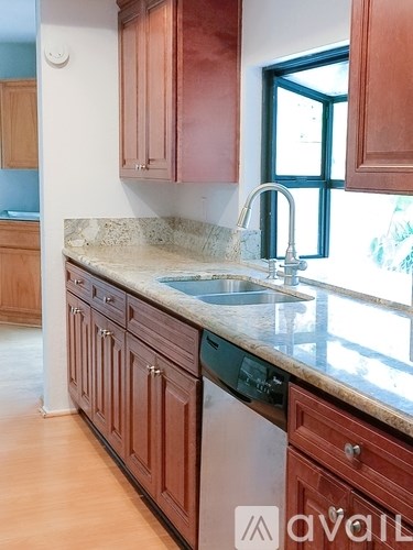 A kitchen with brown cabinets and a marble countertop.