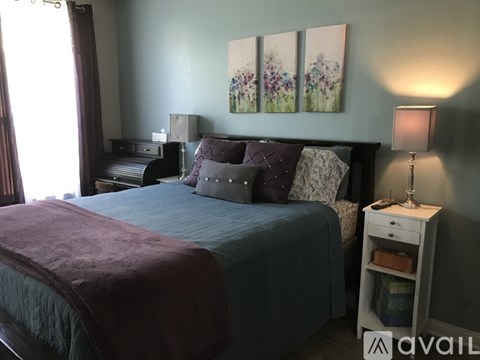 A bedroom with a bed, nightstand, and a painting on the wall.