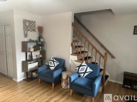 A living room with a blue couch and a wooden staircase.