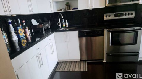 A modern kitchen with black countertops and stainless steel appliances.