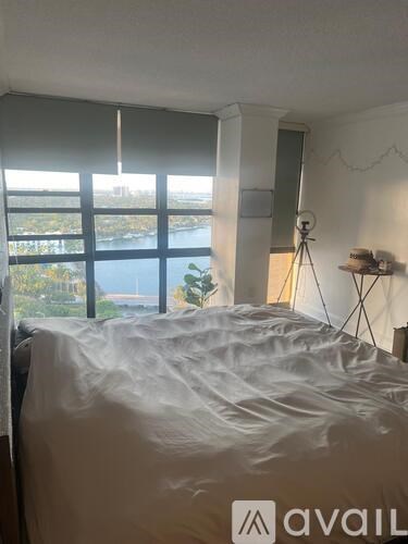 A bedroom with a large bed and a window overlooking a body of water.