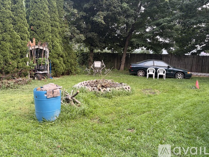 A blue barrel is on a grassy area next to a tree.