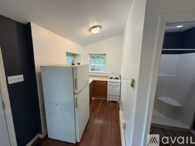 A small kitchen with a refrigerator, a washing machine, and a window.