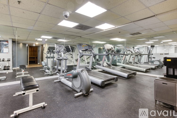 A gym with a variety of exercise equipment including treadmills, stationary bikes, and weight machines.