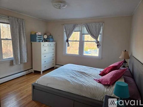 A bedroom with a bed, dresser, and window.