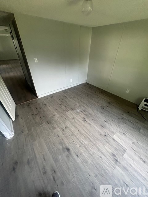 A room with wooden flooring and a white wall.