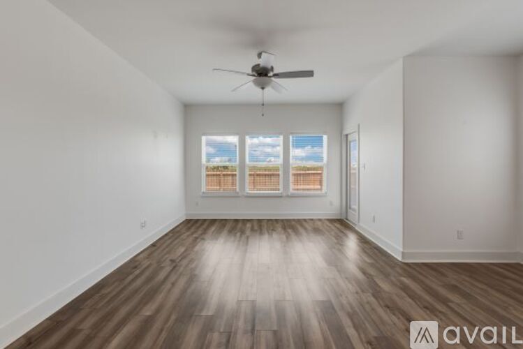 A spacious room with a ceiling fan and wooden flooring.