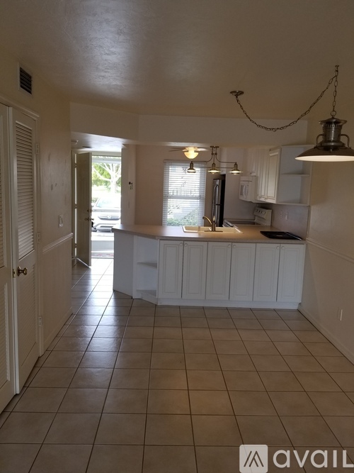 A kitchen with white cabinets and a tile floor.