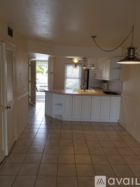 A kitchen with white cabinets and a tile floor.