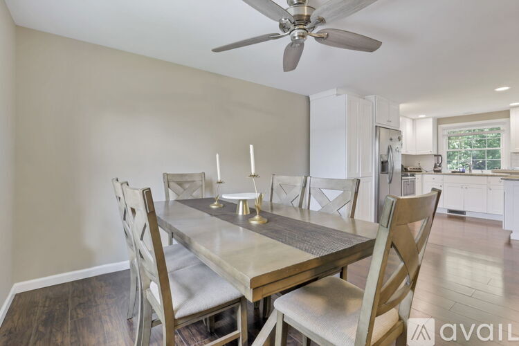 A dining room with a table and chairs and a fan.