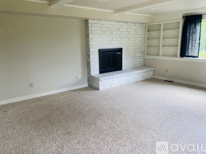 A living room with a fireplace and carpeted floor.