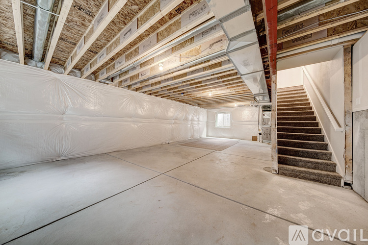 A spacious attic room with a staircase on the right side.