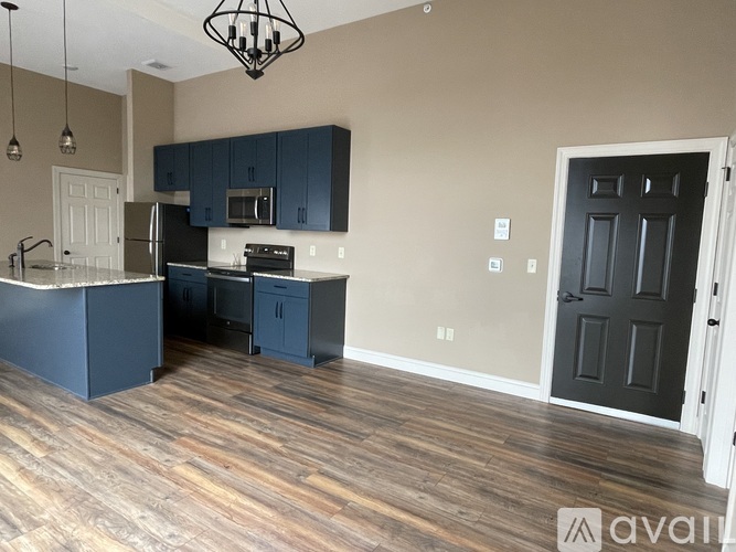 A kitchen with dark blue cabinets and a black door.