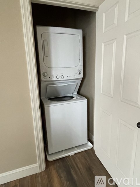 A white dishwasher and dryer are stacked in a narrow space.