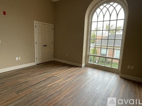 A room with a wooden floor and a large arched window.