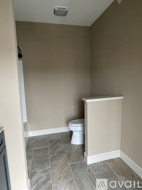A small bathroom with a toilet and tiled floor.