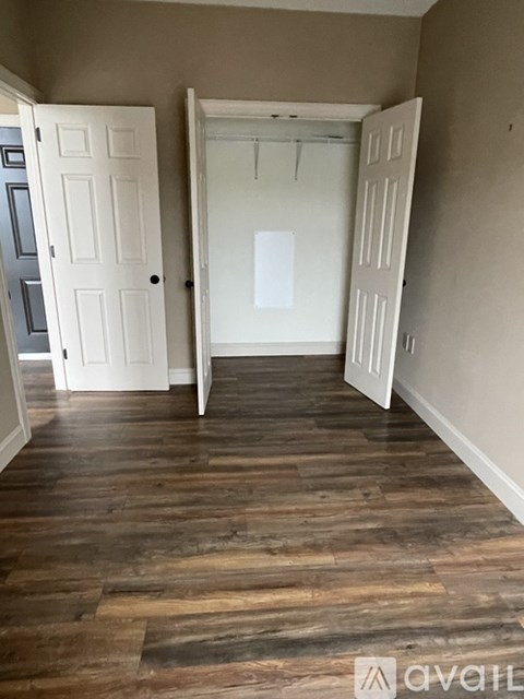 A room with a wooden floor and two white doors.