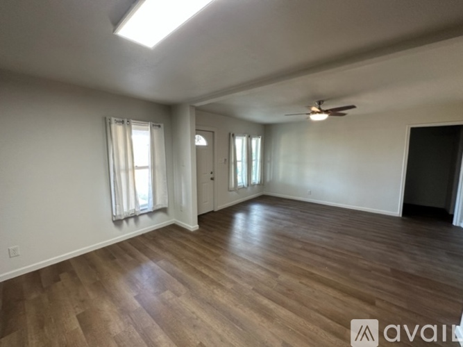 A spacious room with wooden flooring and a ceiling fan.