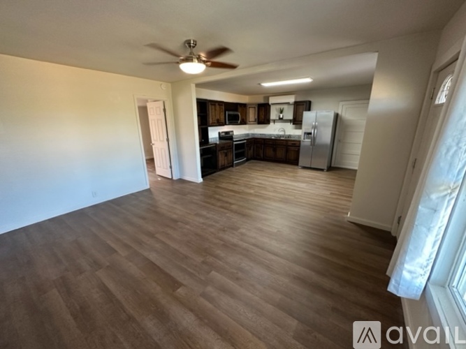 A spacious kitchen and living room with wooden flooring and white walls.