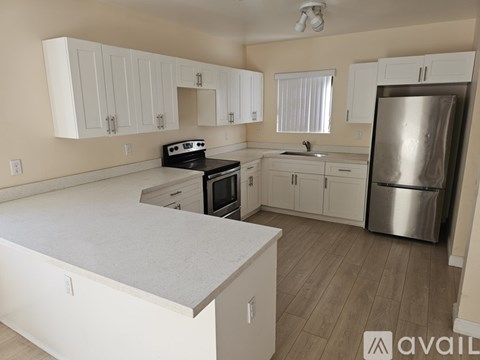 A kitchen with white cabinets and a stainless steel refrigerator.